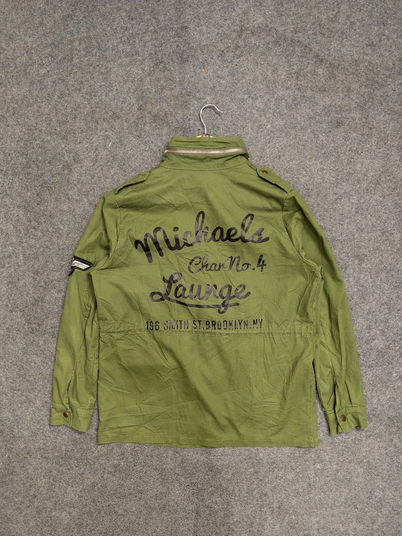M65 Military Jacket (Category: Coats, Jackets and Outerwear) located in Cordova. Submitted by bsb.streetluxvintage.clothing (Listing ID 1459790252, Image 2). Description: - Olive green utility jacket - Multiple front pockets - 'U.S 831 NINE' text on chest - Patch on sleeve - 'Michaels Lounge Char No.4 196 Smith St. Brooklyn NY' back graphic - Zipper closure - High collar.