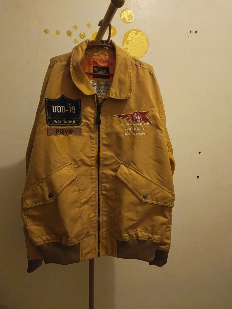 Mens bomber Jacket (Category: Coats, Jackets and Outerwear) located in Mandaluyong City. Submitted by apparel_jenjo (Listing ID 1459860230, Image 3). Description: Silhouette: Classic loose-fit aviator bomber jacket styling featuring a zip front closure and rib-knit cuffs, collar, and hem. [1, 2] Front Details: Right breast features a prominent patch with the text "UOD-79" and "PISVIP". Left breast displays a stylized red chevron pennant patch and