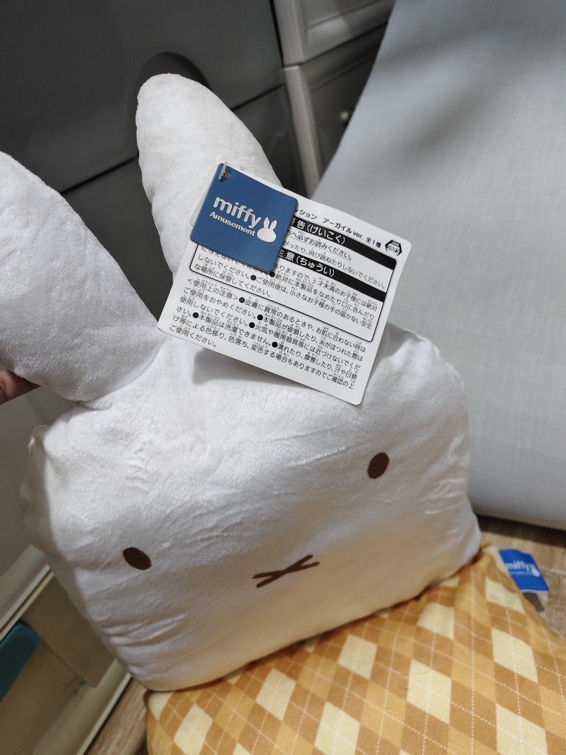 Miffy Amusement Plush Pillow with Argyle Pattern Base (Category: Plushies & Soft Toys) located in Makati City. Submitted by abegailbrezuela (Listing ID 1459783801, Image 2). Description: - Adorable Miffy plush pillow - Classic Miffy face on a soft white plush body - Comes with a separate cushion featuring a brown and yellow argyle pattern - Original tags still attached - Ideal for Miffy fans and as a charming room decoration.