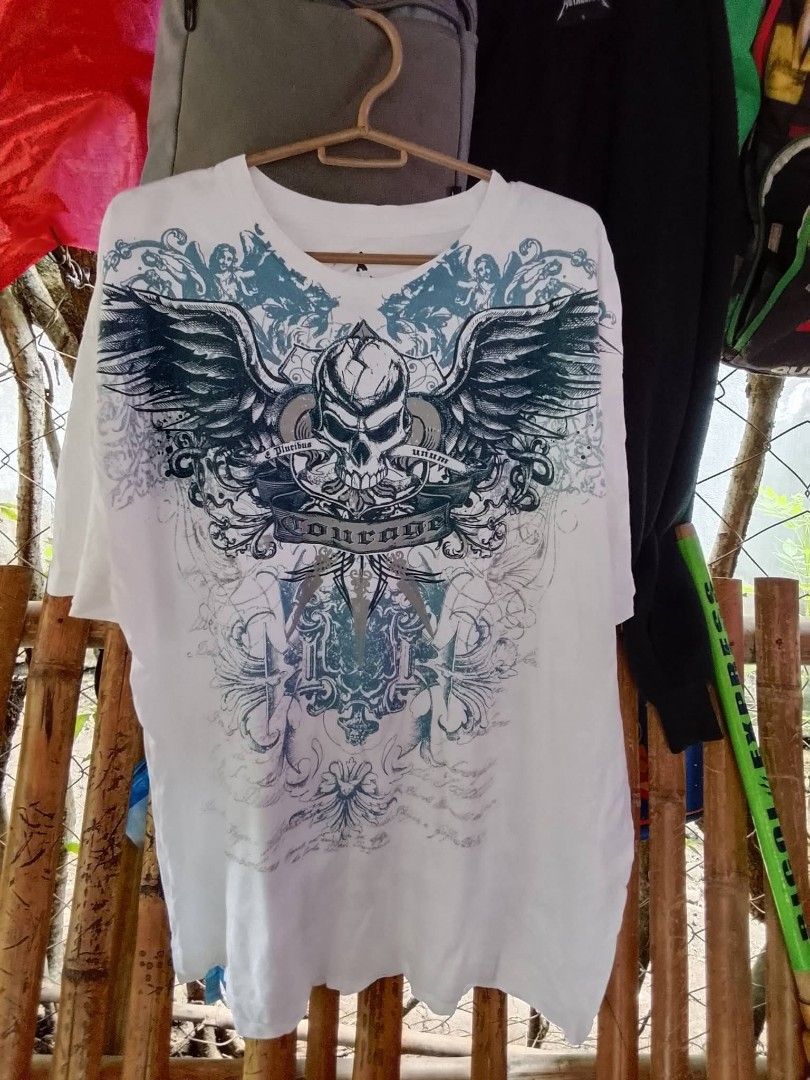 MMA elite (Category: Activewear) located in Pili. Submitted by alexsanandres412 (Listing ID 1459769031, Image 1). Description: - Classic white t-shirt - Large front graphic: Skull with wings and ornate details - Back design: Fleur-de-lis with text - Ideal for casual wear - Check photos for complete design.