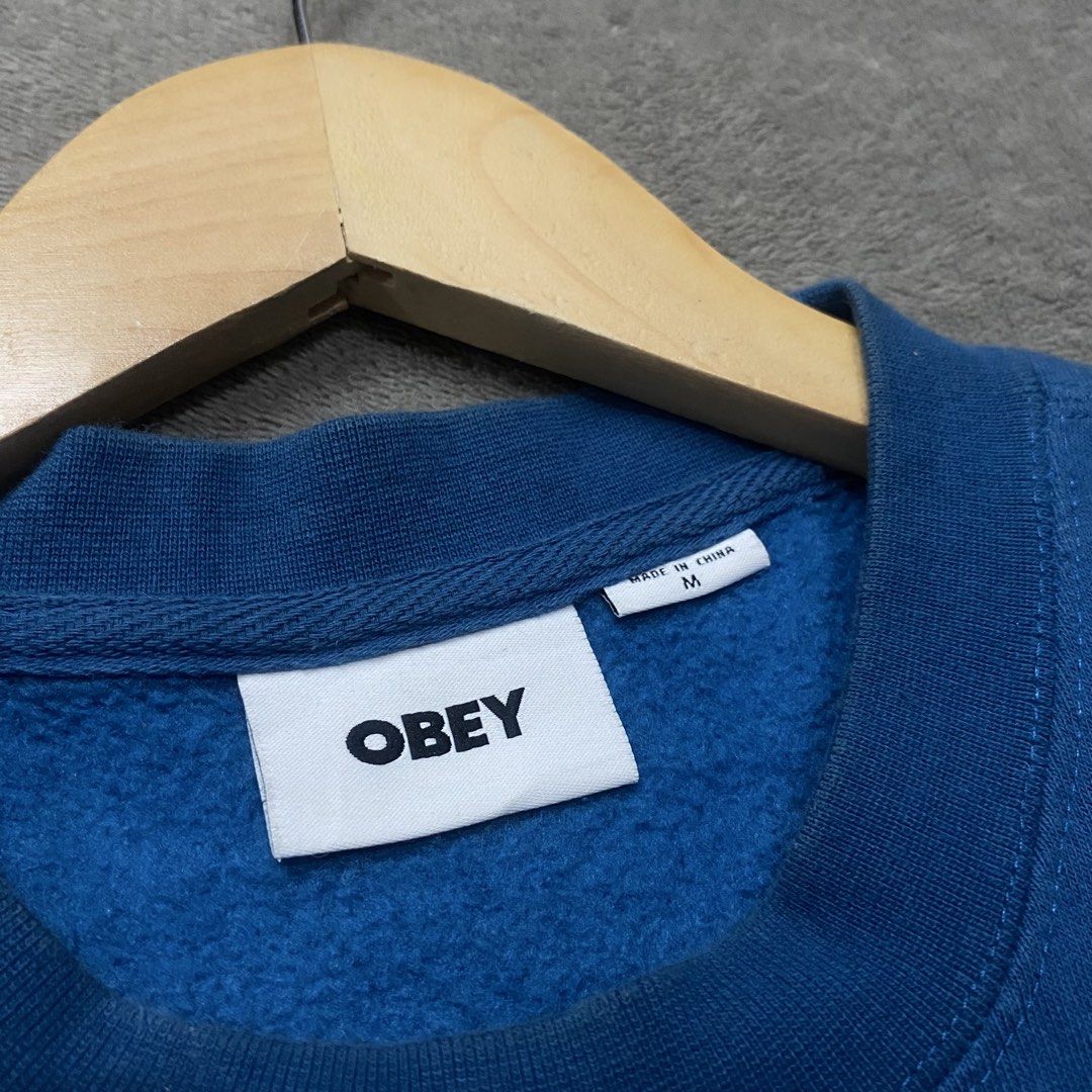 OBEY Blue Graphic Sweatshirt Size M (Category: Coats, Jackets and Outerwear) located in Naga. Submitted by ejdurante17 (Listing ID 1459745941, Image 3). Description: - Brand: OBEY - Color: Blue - Size: Medium (M) on tag but dimension is (L: 28” x W: 23”) can fit up to Large - Design: Features a unique graphic print of a hand holding a flower on the front. - Material: Comfortable cotton and polyester blend. - Style: Ideal for casual everyday wear.