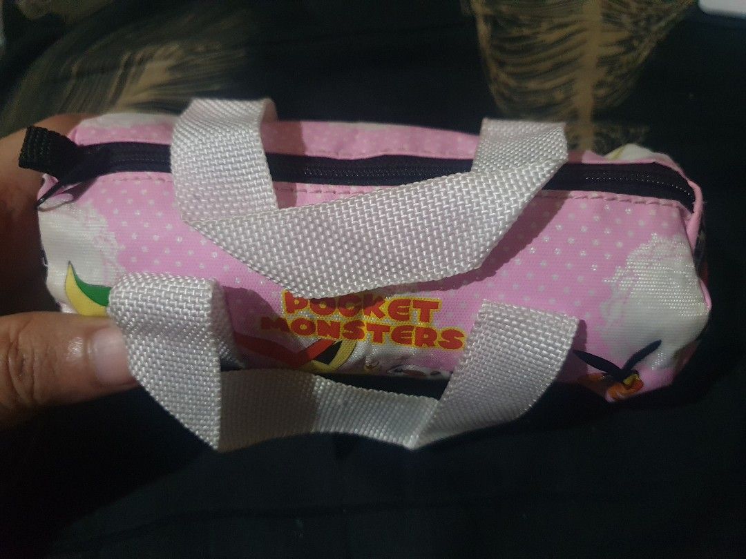 Pokemon "Pocket Monsters" mini Duffle Pouch Bag (Category: Purses & Pouches) located in Quezon City. Submitted by collectionneursonline88 (Listing ID 1459809843, Image 3). Description: - Adorable pink pouch featuring popular Pokemon characters: Pikachu, Snivy, Oshawott, Torchic, and Victini. - "Pocket Monsters" and "Best Wishes" text adds a nostalgic touch. - Features a secure zipper closure and two convenient handles. - Ideal for organizing and 