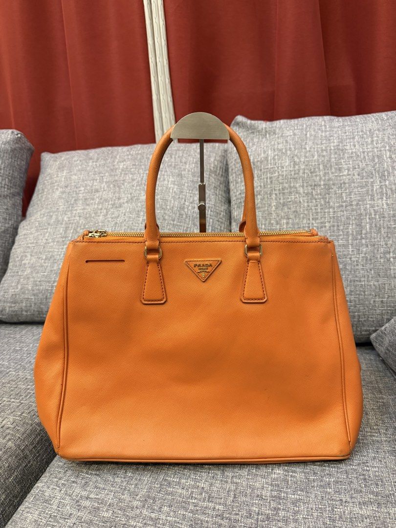 Prada Saffiano Lux Tote Orange (Category: Luxury Bags & Wallets) located in San Jose. Submitted by affordabletrendsby_cai (Listing ID 1459731119, Image 3). Description: - Authentic Orange Prada Saffiano Lux Tote - Elegant Gold Hardware - Secure Zipper Closure - Comfortable Top Handles - Signature Prada Triangle Logo - Spacious Interior for Essentials - Ideal for Everyday Errands or Travel.