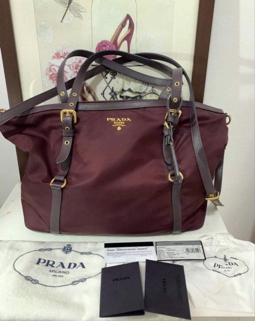 Prada Tessuto Saffiano Burgundy (Category: Luxury Bags & Wallets) located in San Antonio. Submitted by hANNdpicked (Listing ID 1459694114, Image 1). Description: - Authentic Prada tote bag - Color: Burgundy - Material: Nylon with grained leather trim - Hardware: Gold details - Includes: Dust bag and authenticity cards - Features: Spacious interior - Versatile: Can be worn as a shoulder bag or tote -Like new.