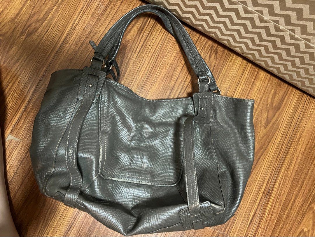 PRELOVED Kooba Hobo Bag (Category: Shoulder Bags) located in Ternate. Submitted by snvillena798 (Listing ID 1459718830, Image 2). Description: bought secondhand RFS: masyadong mabigat para magamit ko sa school hehe - Dark grey shoulder bag - Textured faux leather finish - Multiple zippered pockets on the front - Main compartment for storage - Adjustable straps for comfort - Silver-tone hardware - Ideal for everyday style.