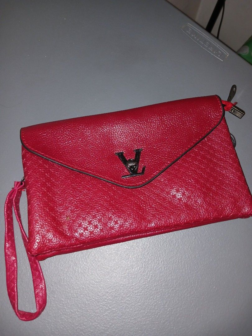 Red Envelope Clutch Bag with 'LV' Logo (Category: Luxury Bags & Wallets) located in Quezon City. Submitted by rdonelle (Listing ID 1459775135, Image 1). Description: - Red textured clutch bag - Envelope style with black trim - Prominent black 'LV' logo on the front - Includes a small wrist strap - Ideal for evenings or as a statement piece.
