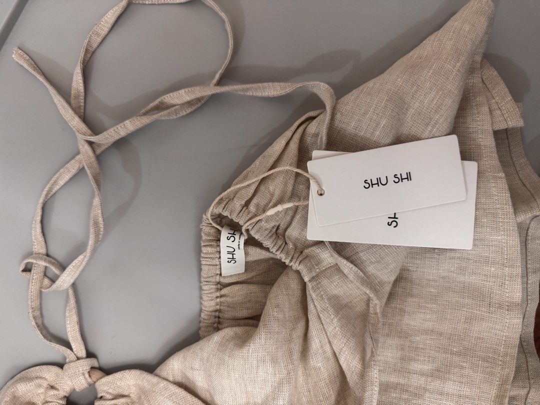 SHU SHI Linen Halter Top - Beige (Category: Sleeveless) located in Makati City. Submitted by prelovedbymich. (Listing ID 1459740243, Image 3). Description: - Brand: SHU SHI - Color: Beige - Size S - Style: Halter Top - Material: Linen - Condition: Brand new with tags attached - RFS: bought 2 by mistake.
