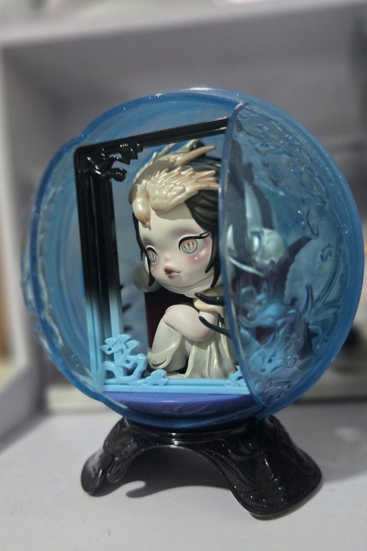 "The Frame" SKULLPANDA The Mirage Series (Category: Designer & Blind Box Toys) located in Manila. Submitted by fierceriver.e57033 (Listing ID 1459793551, Image 2). Description: - Adorable collectible figure - Encased in a blue crystal ball - Figure has big eyes and unique hairstyle - Sitting pose with red cloth accent - Crystal ball features intricate external designs - Includes a sturdy black stand - Ideal display piece for collectors.