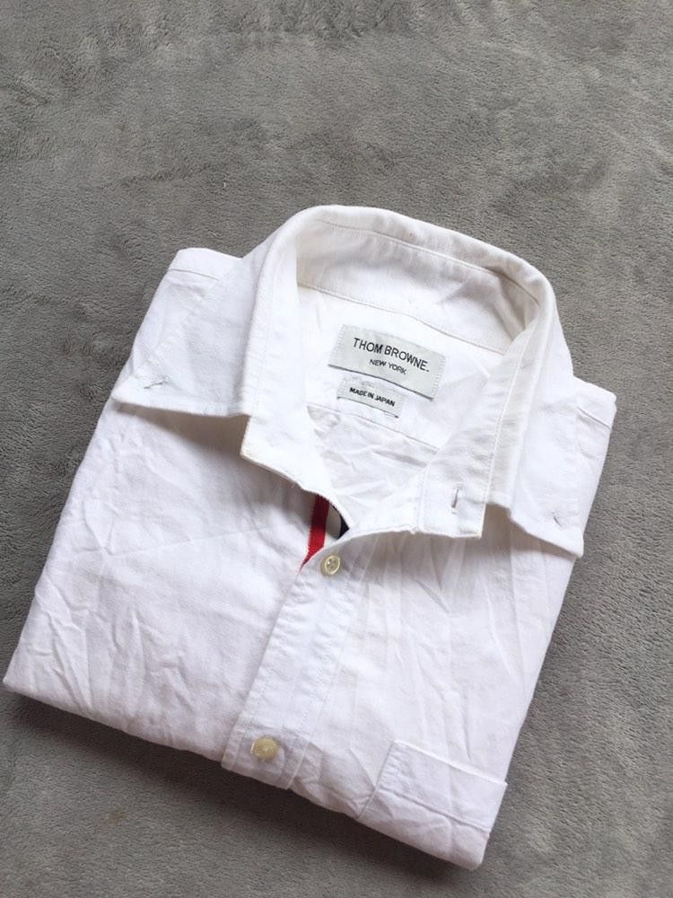 Thom Browne Oxford Button Down Shirt Size 2 (Category: Activewear) located in Manila. Submitted by niggzreyno51476 (Listing ID 1459852191, Image 2). Description: - Classic white Oxford button-down shirt - Brand: Thom Browne - Signature red, white, and blue stripe detail - Made in Japan - Size: 2 - Ideal for smart casual outfits.