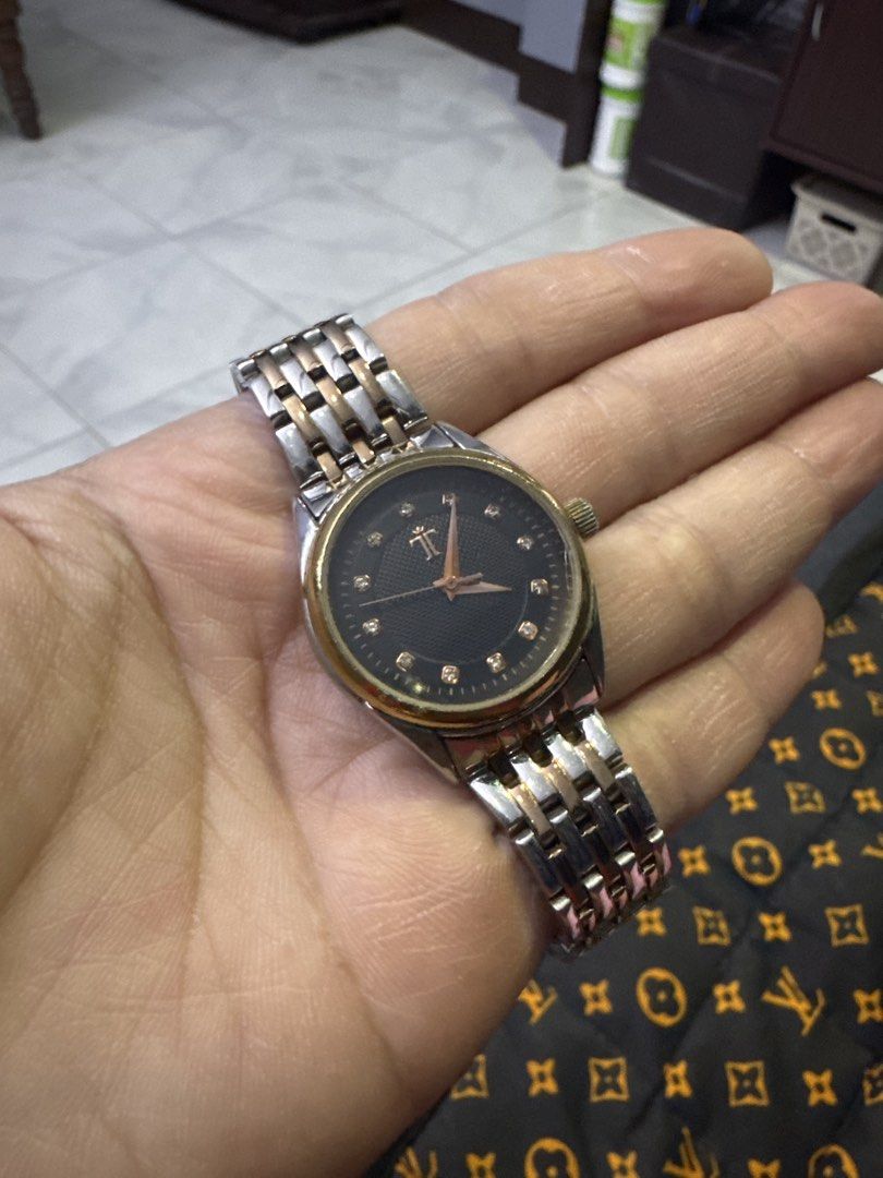 Two-tone Watch with Diamond Markers (Category: Women's Watches) located in Valenzuela. Submitted by arizanatividad (Listing ID 1459805944, Image 1). Description: - Classic round watch face - Black dial with sparkling diamond markers - Elegant silver and rose gold tone band - Convenient right-side crown - A perfect accessory to elevate any outfit.