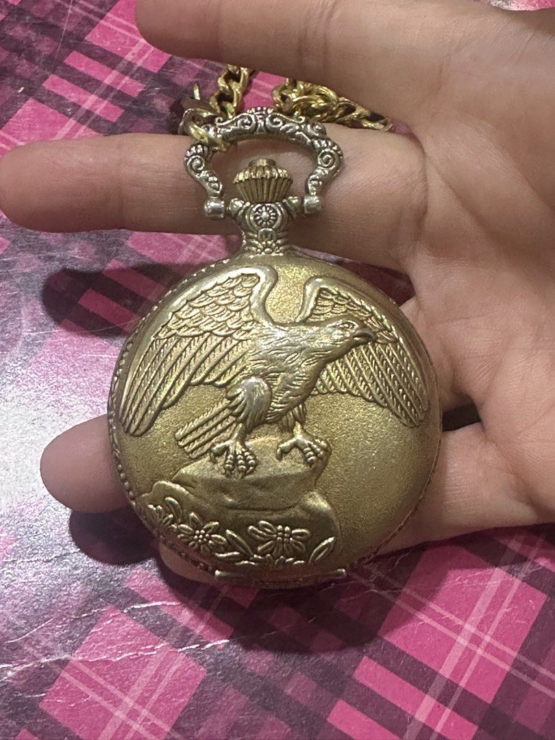 Vintage Gold Eagle Pocket Watch with Chain (Category: Women's Watches) located in Manila. Submitted by roseluxuryitems (Listing ID 1459718654, Image 2). Description: - Gold-tone pocket watch - Features an eagle design on the front cover - Intricate scrollwork on the back - White watch face with black numbers and hands - Quartz movement - Comes with a matching gold chain - Ideal for collectors or as a unique accessory.