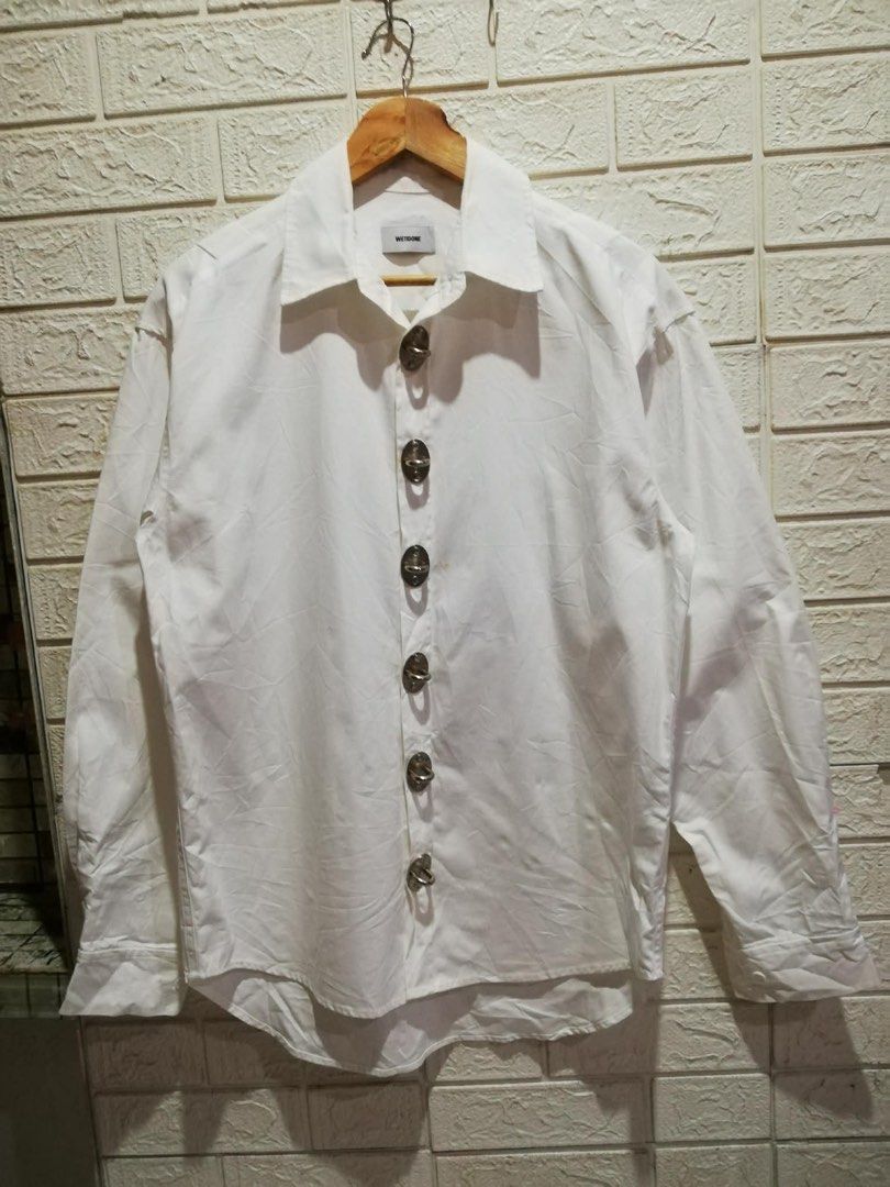 WE11DONE White Oversized Shirt with Unique Buttons (Category: Tshirts & Polo Shirts ) located in Rizal. Submitted by tiangarcia02 (Listing ID 1459814706, Image 1). Description: - Authentic WE11DONE white long-sleeved shirt - Unique large silver button-down front - Relaxed, oversized fit - Versatile for layering or standalone wear - Refer to label for care instructions.