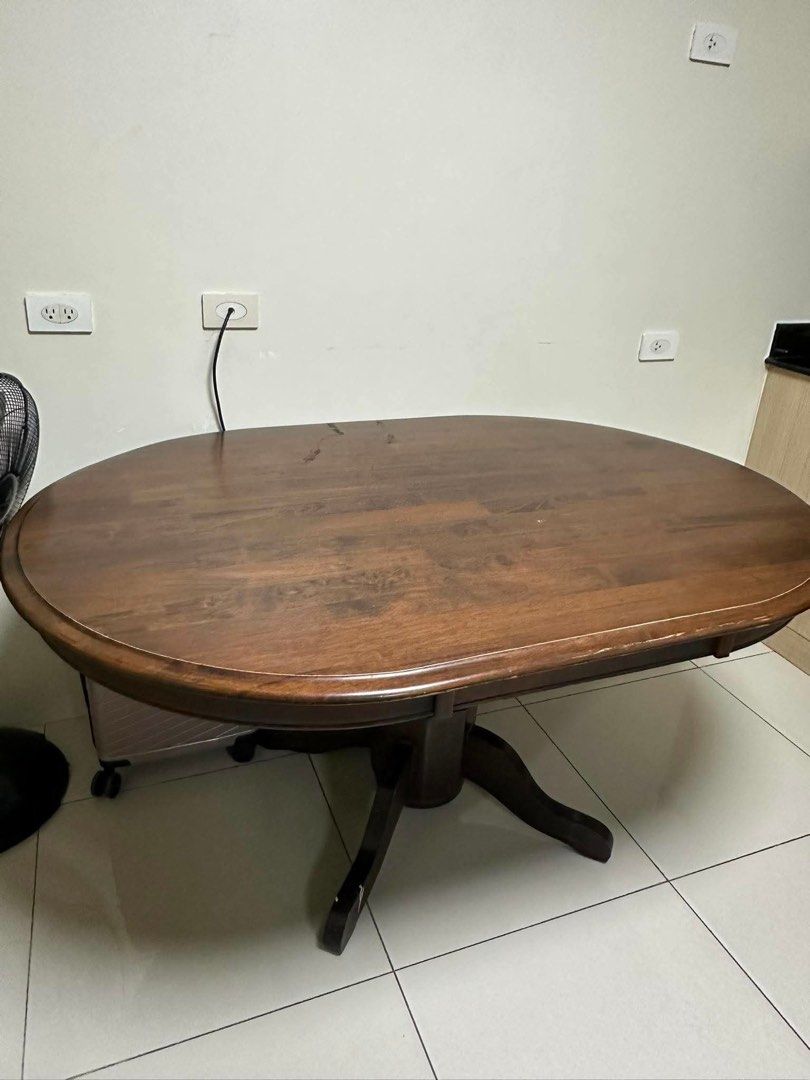 Wooden Oval Dining Table (Category: Tables & Sets) located in Quezon City. Submitted by cheetowsz (Listing ID 1459837949, Image 2). Description: - Solid wood oval dining table - Rich, dark brown finish - Sturdy pedestal base - Minor scuffs on legs and surface (normal wear) - Ideal for family meals and entertaining guests.