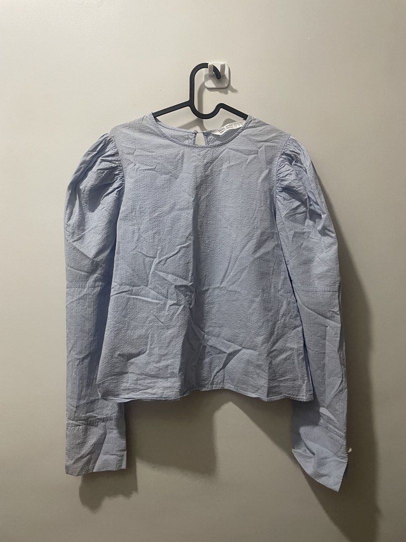 Zara Basic Denim Light Blue Puff Sleeve Top (Category: Blouses) located in Binan City. Submitted by dearlouise (Listing ID 1459847955, Image 1). Description: - Zara Basic light blue top - Features puff sleeves - Buttoned cuffs with pearl-like buttons - Textured fabric - Keyhole opening at the back with button closure - Flaw: missing pearl button (right cuff).