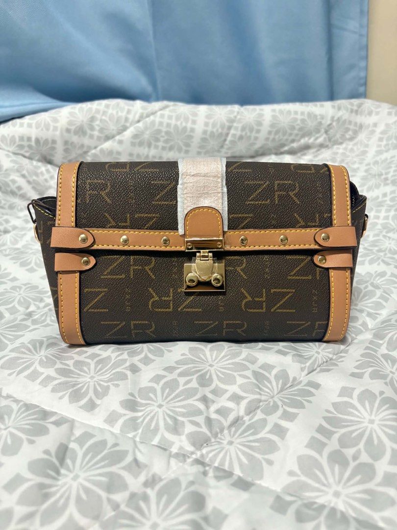 ZR Monogram Trunk Bag (Category: Luxury Bags & Wallets) located in Manila. Submitted by vengonflo (Listing ID 1459793248, Image 1). Description: - Stylish brown ZR monogram trunk bag - Elegant tan trim and gold hardware - Secure clasp closure - Adjustable strap for comfort - Compact, mini trunk design - Ideal for carrying daily essentials.
