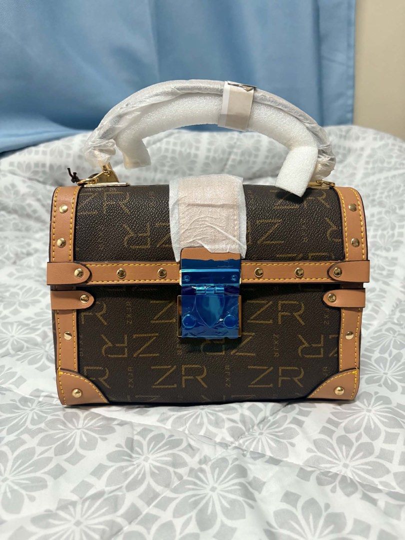 ZR Monogram Trunk Bag with Blue Clasp (Category: Luxury Bags & Wallets) located in Manila. Submitted by vengonflo (Listing ID 1459793125, Image 1). Description: - Cute little trunk bag - Brown with all-over ZR monogram - Tan trim and gold hardware - Shiny blue clasp closure - Top handle wrapped in plastic.