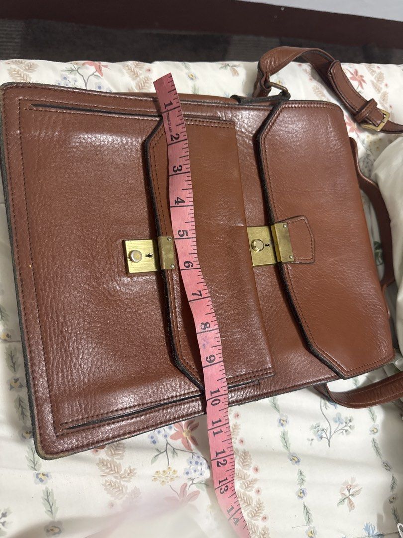 2027 Brown Leather Handbag with Brass Hardware (Category: Luxury Bags & Wallets) located in Silang. Submitted by sari2bilina (Listing ID 1459927524, Image 2). Description: - Classic brown leather handbag - Two front pockets with brass clasps - Spacious main compartment - Adjustable shoulder strap - Ideal for everyday use or work - Approximate dimensions: 10 inches tall x 8 inches wide with japanese character sa loob.