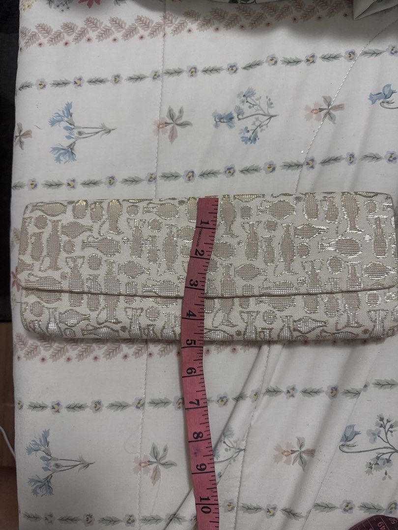 2027 Gold and White Patterned Clutch Bag (Category: Clutches) located in Silang. Submitted by sari2bilina (Listing ID 1459922563, Image 1). Description: - Chic gold and white patterned clutch - Secure snap closure - Soft peachy-pink fabric lining inside - Dimensions: Approx. 10 inches long, 3 inches wide - Ideal for evening wear and special occasions.