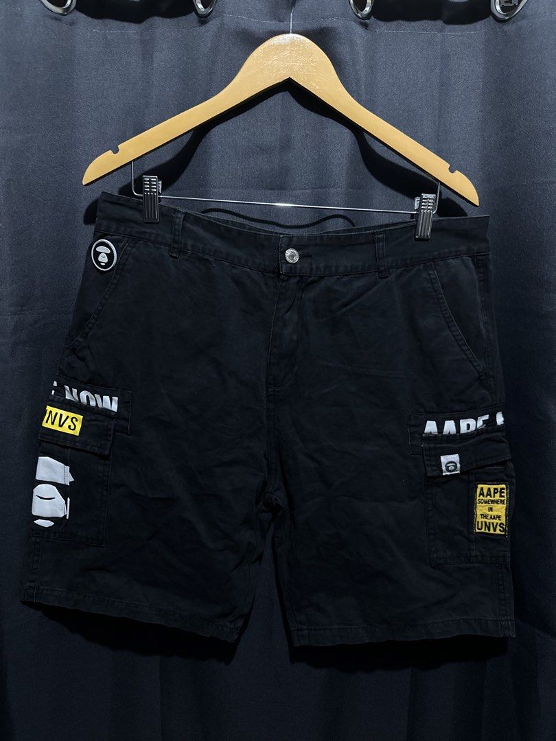 AAPE BY A BATHING APE Cargo Shorts (Category: Shorts) located in Buenavista. Submitted by themodernrack (Listing ID 1460042888, Image 1). Description: Brand: AAPE BY *A BATHING APE Color: Black Style: Graphic Cargo Shorts (Features signature AAPE graphic prints, AAPE UNVS patches, rubberized Moon Face emblem on front hip, branded waist button, rear flap pocket with brand tag, and back text graphic print) Tag Size: Unspecified / Standard Fit Condi