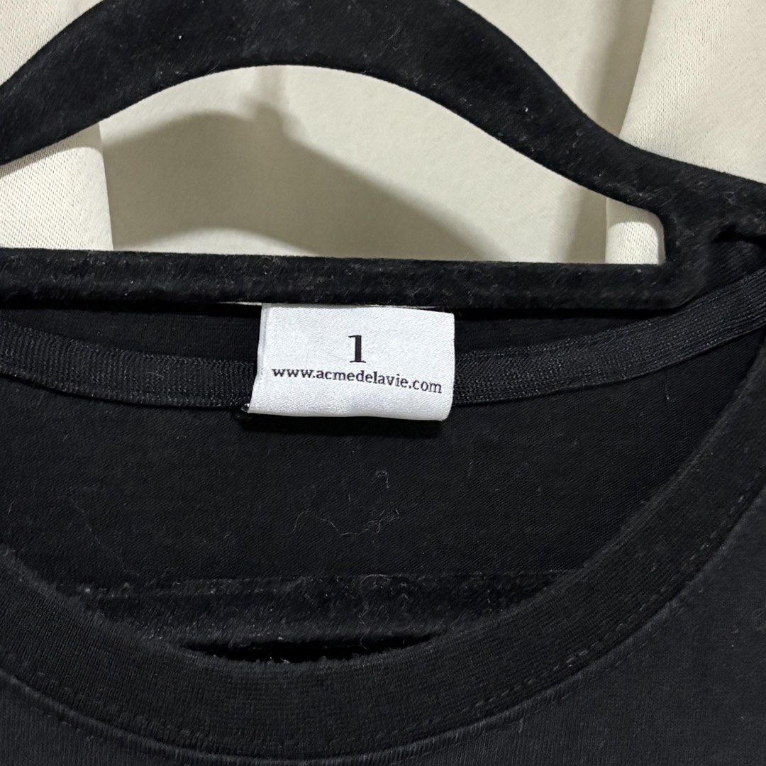 ACMÉ DE LA VIE (Category: Tshirts & Polo Shirts ) located in Quezon City. Submitted by grailph (Listing ID 1460035041, Image 3). Description: - Brand: ACMÉ DE LA VIE (ADLV) - Color: Black - Color rate 9/10 - Size 1 On tag - Dimensions 22”x29” boxy fit - Material: 100% Cotton - Design: Features a unique graphic print of a child with a cookie - Condition: Good, pre-loved - Available for meet-up in Commonwealth North Fairview NO CRACKPRINTS -Minor r