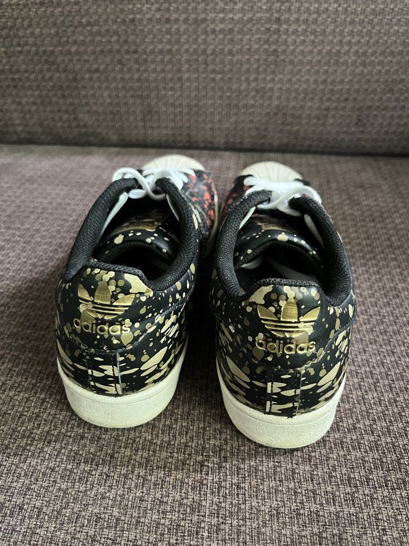Adidas Superstar Camo Splatter Sneakers (Category: Sneakers) located in Manila. Submitted by lowkeyxan (Listing ID 1459985728, Image 3). Description: Original, Adidas Superstar sneakers with a black base, featuring a cool camo splatter design in orange and gold. Classic shell toe and white laces. Perfect for everyday style. .