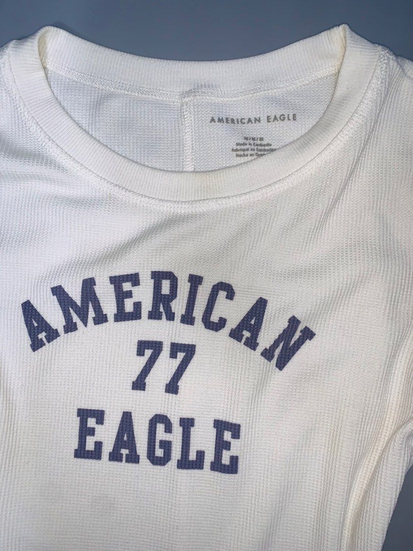 American Eagle 77 White Thermal Long Sleeve Top (Category: Longsleeves) located in Dagupan City. Submitted by sj_styles0910. (Listing ID 1460096142, Image 2). Description: - Brand: American Eagle - Style: Long sleeve thermal top - Design: Features 'American Eagle 77' graphic on the front - Material: Comfortable waffle knit - Versatile: Great for layering or wearing alone - Easy to style: Pairs well with jeans or shorts.