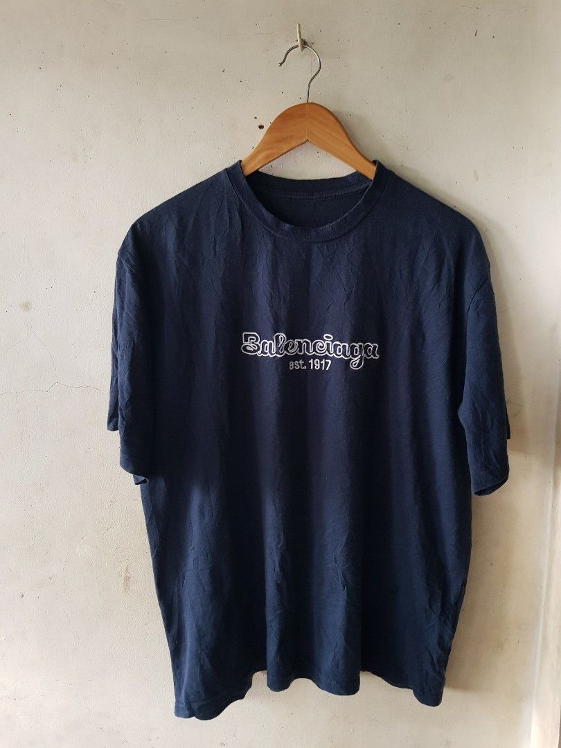 Balenciage Logo Tee T Shirt (Category: Luxury Apparel) located in Santo Domingo. Submitted by jcobedoza213916 (Listing ID 1459982811, Image 1). Description: balenciaga Logo Tee T Shirt Unisex Men's & Women's Width 22 lenght 27 Embroid Front Logo Balenciaga Est 1917 Made In Portugal color Navy Blue size on tag LARGE excellent condition color rate 9.6/10 necktag Cut Tag no issue: No Pinhole No Flaws No Discoloration.