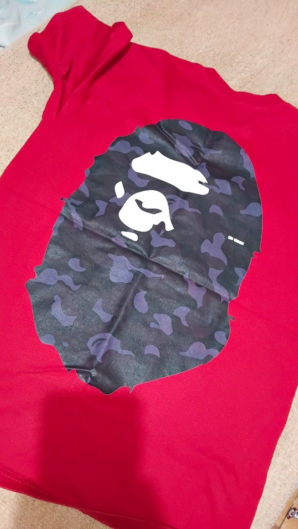 BAPE Red Camo Ape Head T-Shirt (Category: Tshirts & Polo Shirts ) located in Muntinlupa City. Submitted by zlysiea (Listing ID 1459955171, Image 1). Description: - Authentic Red BAPE T-Shirt - Features iconic Ape Head logo - Stylish black and purple camo pattern - Perfect for any streetwear enthusiast - A classic BAPE piece to add to your collection.