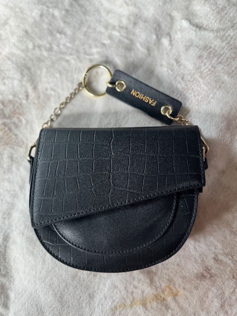 Black Croc Embossed Saddle Bag with Chain Strap (Category: Luxury Bags & Wallets) located in Caloocan City. Submitted by eogg30 (Listing ID 1460074996, Image 2). Description: - Cute black saddle bag - Croc embossed texture - Gold chain strap - Small 'FASHION' tag detail - Ideal for going out or elevating your look - Fits essentials: phone, wallet, keys - Secure flap closure.