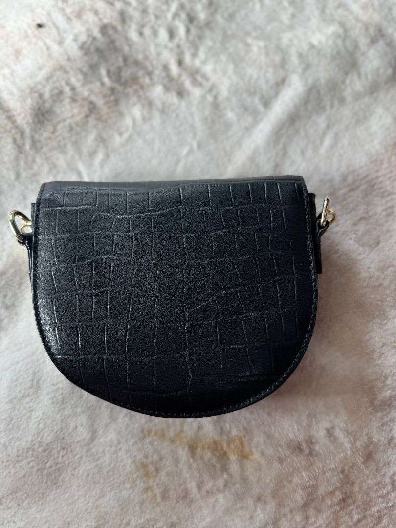 Black Croc Embossed Saddle Bag with Chain Strap (Category: Luxury Bags & Wallets) located in Caloocan City. Submitted by eogg30 (Listing ID 1460074996, Image 3). Description: - Cute black saddle bag - Croc embossed texture - Gold chain strap - Small 'FASHION' tag detail - Ideal for going out or elevating your look - Fits essentials: phone, wallet, keys - Secure flap closure.