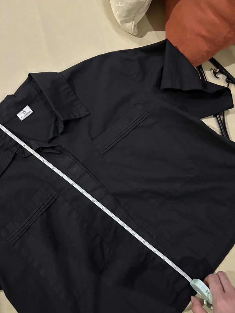 Black Short Sleeve Button Up Shirt with Pockets (Category: Blouses) located in Cainta. Submitted by unboxingstuff (Listing ID 1460053193, Image 2). Description: - Classic black short sleeve button-up shirt - Features two pleated chest pockets - Versatile for casual outfits or as a layering piece - Free size; can fit M-L - Semi-cropped .