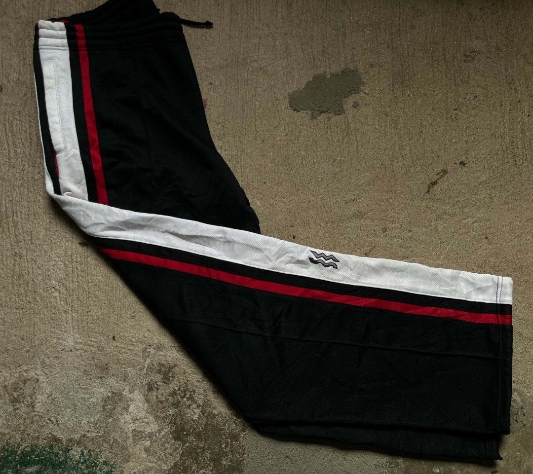SUPERSTAR Black Track Pants with Red and White Stripes (Category: Coats, Jackets and Outerwear) located in Vallehermoso. Submitted by threy (Listing ID 1459923739, Image 2). Description: - Black track pants - Bold red and white stripes down the sides - Elastic waistband with drawstring - Two logos on the right leg - Comfortable and stylish for casual wear or sports.