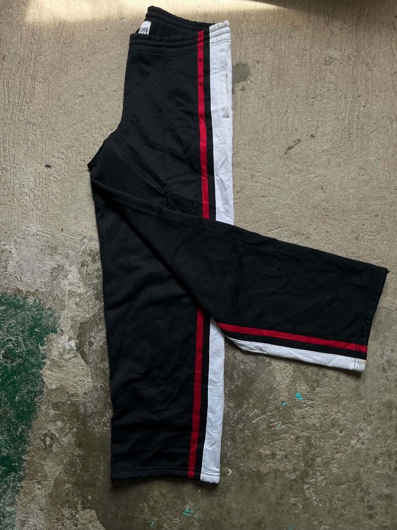 SUPERSTAR Black Track Pants with Red and White Stripes (Category: Coats, Jackets and Outerwear) located in Vallehermoso. Submitted by threy (Listing ID 1459923739, Image 3). Description: - Black track pants - Bold red and white stripes down the sides - Elastic waistband with drawstring - Two logos on the right leg - Comfortable and stylish for casual wear or sports.