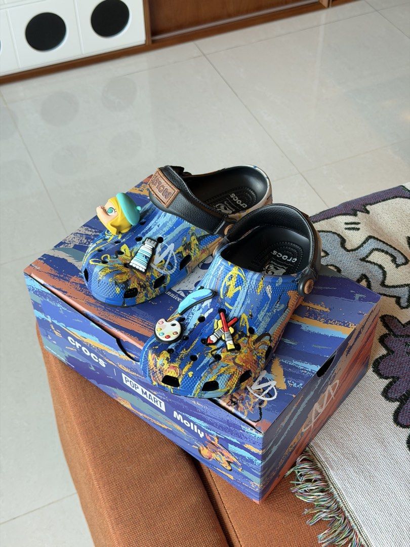 Crocs x Pop Mart Molly Artist Collection Clogs (Category: Slippers and slides) located in Taguig. Submitted by Yukandfriends (Listing ID 1459994222, Image 1). Description: - Authentic Crocs x Pop Mart Molly collaboration clogs. - Features an artist theme with unique paint tube and palette Jibbitz. - Stylish blue base with an abstract paint splatter design. - Comes complete with the original box. - A must-have for collectors and fans of Molly and 