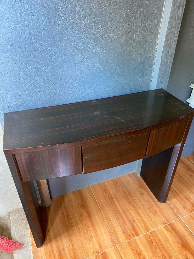 Dark Wood Console Table with 3 Drawers (Category: Tables & Sets) located in Minglanilla. Submitted by naquilagretchen (Listing ID 1460038607, Image 3). Description: - Stylish dark wood console table - Unique curved front design - Three smooth-gliding drawers for storage - Beautiful natural wood grain pattern - Minor scratches on the top surface, adding character - Ideal for entryways, hallways, or as a chic side table - Dimensions: Approximately 