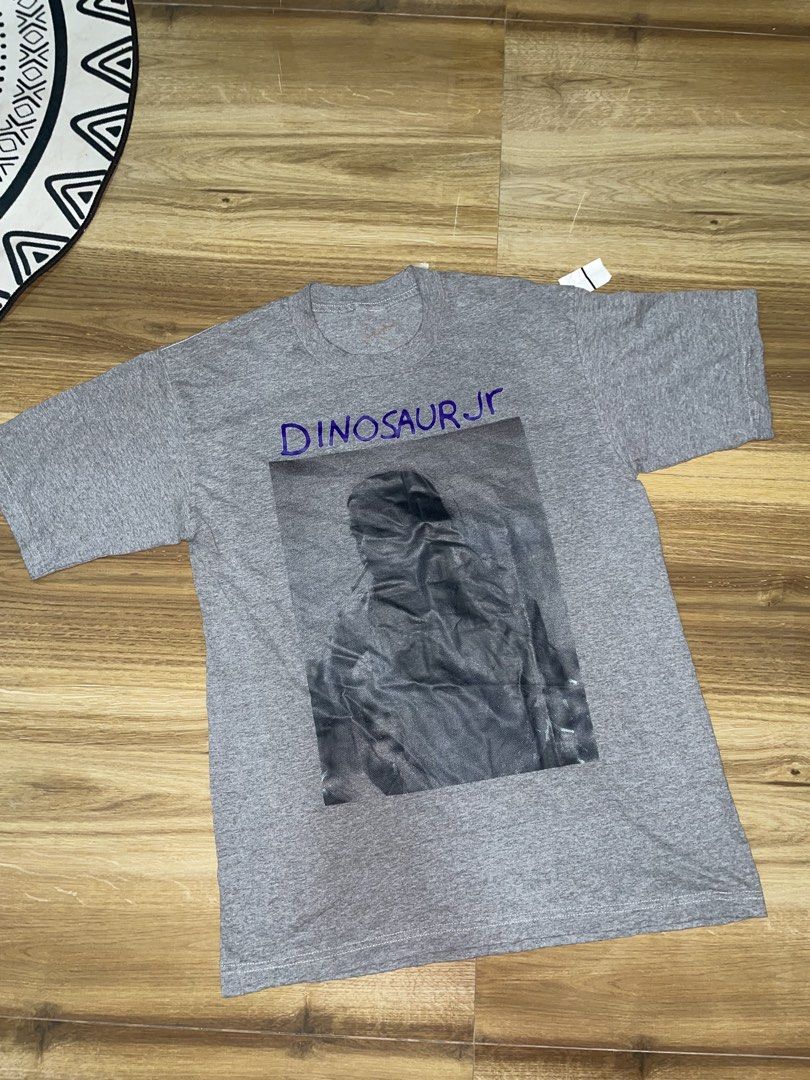 Dinosaur Jr. Graphic T-Shirt (Category: Tshirts & Polo Shirts ) located in Manila. Submitted by clementdav22513 (Listing ID 1460033263, Image 1). Description: - Grey t-shirt with Dinosaur Jr. graphic print - Band name "Dinosaur Jr." in purple text above graphic - Stain present on the inside collar area - Original tag still attached - Size: Small.