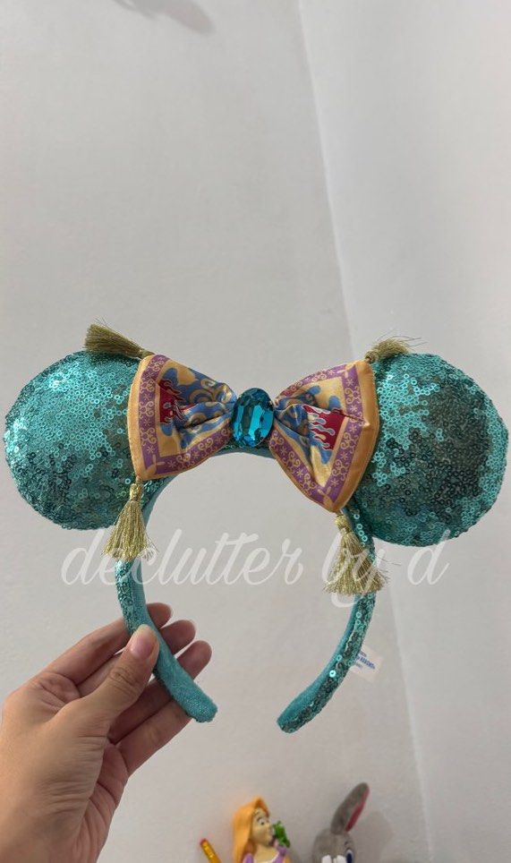 Disney Magic Carpet aladdin Ears jasmine Headband (Category: Handmade Craft) located in Muntinlupa City. Submitted by declutter.by.d (Listing ID 1459994704, Image 1). Description: - Eye-catching turquoise sequin Minnie Mouse ears. - Unique bow designed like Aladdin's magic carpet. - Features decorative tassels on the sides of the bow. - Adorned with a sparkling blue gem in the center of the bow. - A must-have accessory for any Disney enthusiast o