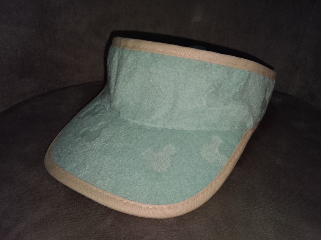 Disney Mickey Mouse Sunvisor (Category: Hats & Beanies) located in Binangonan. Submitted by yuristalin888 (Listing ID 1459940722, Image 2). Description: Add a touch of Disney magic to your sunny days with this charming mint green sun visor. * **Design & Details:** Features an all-over tonal Mickey Mouse silhouette pattern, complemented by contrasting beige trim along the brim and edge. * **Material & Comfort:** Crafted with a soft textured exteri