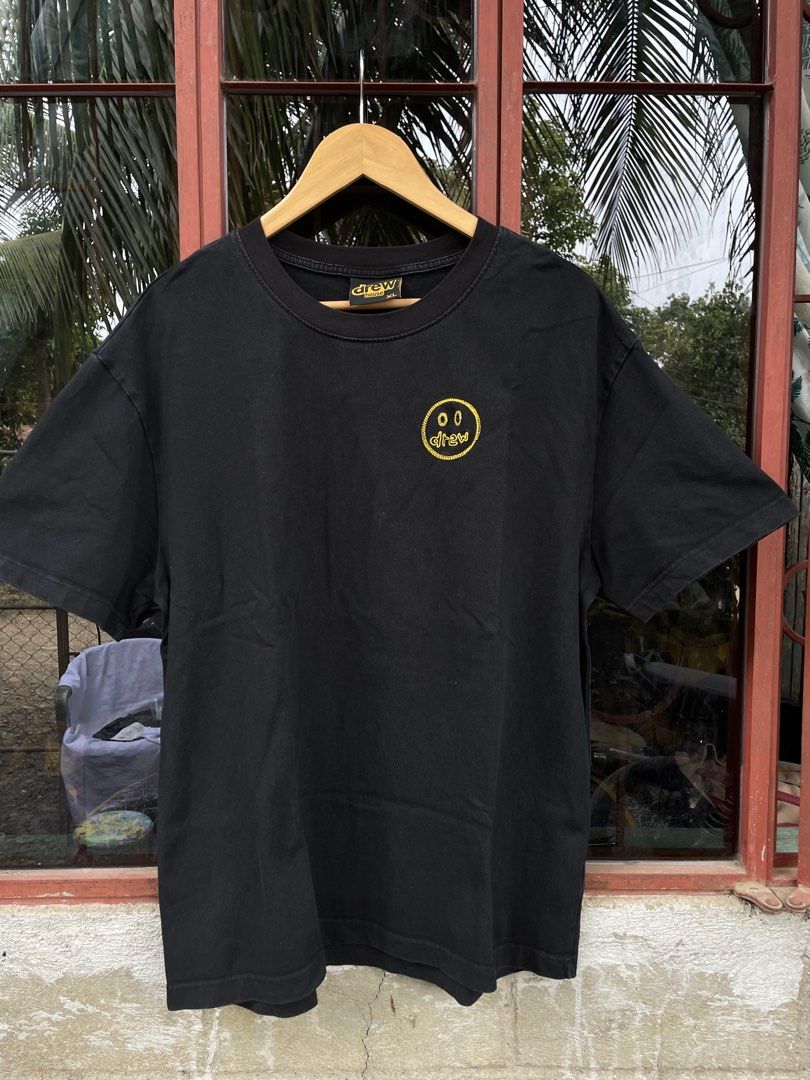 DREW TSHIRT (Category: Tshirts & Polo Shirts ) located in Quezon. Submitted by thriftedbyandie (Listing ID 1460029881, Image 1). Description: This is a black Drew House t-shirt featuring a yellow embroidered sketch mascot smiley face logo on the chest.