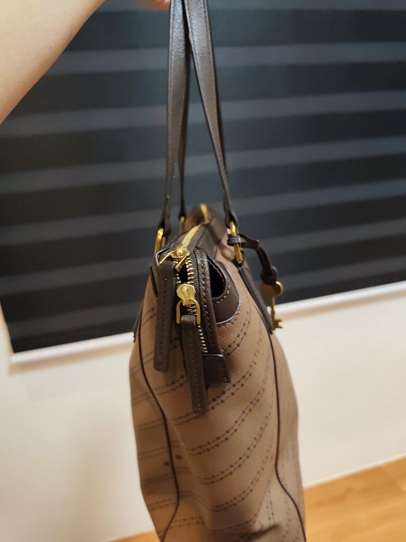 Fossil Brown Monogram Tote Bag with Stripes (Category: Tote Bags) located in Santo Tomas. Submitted by prelovedthrifts (Listing ID 1460019435, Image 2). Description: - Authentic brown Fossil tote bag - All-over signature Fossil monogram pattern - Three vertical stripes (brown & cream) on the front - Genuine leather handles and trim - Secure zipper closure - Multiple interior pockets for organization - Comes with a detachable Fossil key charm This