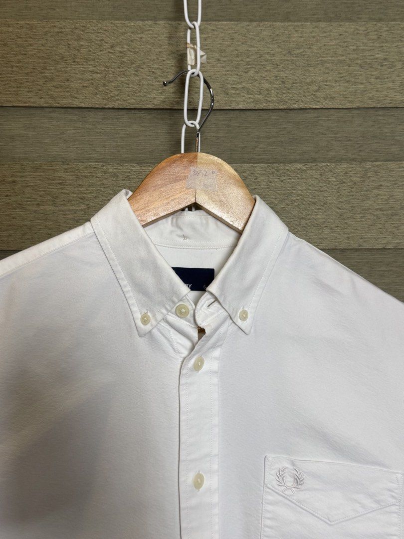 Fred Perry White Button-Down Shirt Size S (Category: Formal Shirts) located in Santa Ana. Submitted by thrift.sanctuary (Listing ID 1460082366, Image 2). Description: - Classic white button-down shirt - Brand: Fred Perry - Iconic embroidered laurel wreath logo on chest pocket - Button-down collar - Long sleeves with button cuffs - Versatile for casual and smart-casual outfits.
