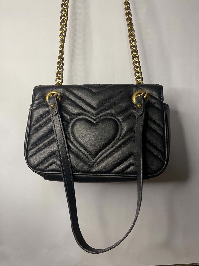 Gucci Marmont Small Shoulder Bag Black Leather (Category: Luxury Bags & Wallets) located in Caloocan City. Submitted by juzootite90264 (Listing ID 1459991997, Image 2). Description: - Black leather shoulder bag - Gold chain strap - Iconic GG logo on front - Heart detail on back - Suede lining interior - Small interior pocket - Gold clasp closure - Versatile for nights out or everyday use.