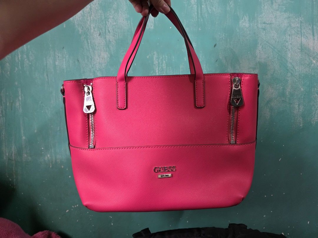 Guess Pink Tote Bag (Category: Tote Bags) located in Quezon City. Submitted by gabbie17 (Listing ID 1459994236, Image 1). Description: Turn heads with this vibrant, eye-catching hot pink GUESS tote! Perfectly structured with a textured saffiano finish, sturdy double top handles, and sleek silver-tone hardware featuring signature GUESS front pocket zipper pulls. ​Condition: Brand New ​Origin: Direct from US ​Price: ₱1,500 ​Color: Hot Pink / Fuchsi
