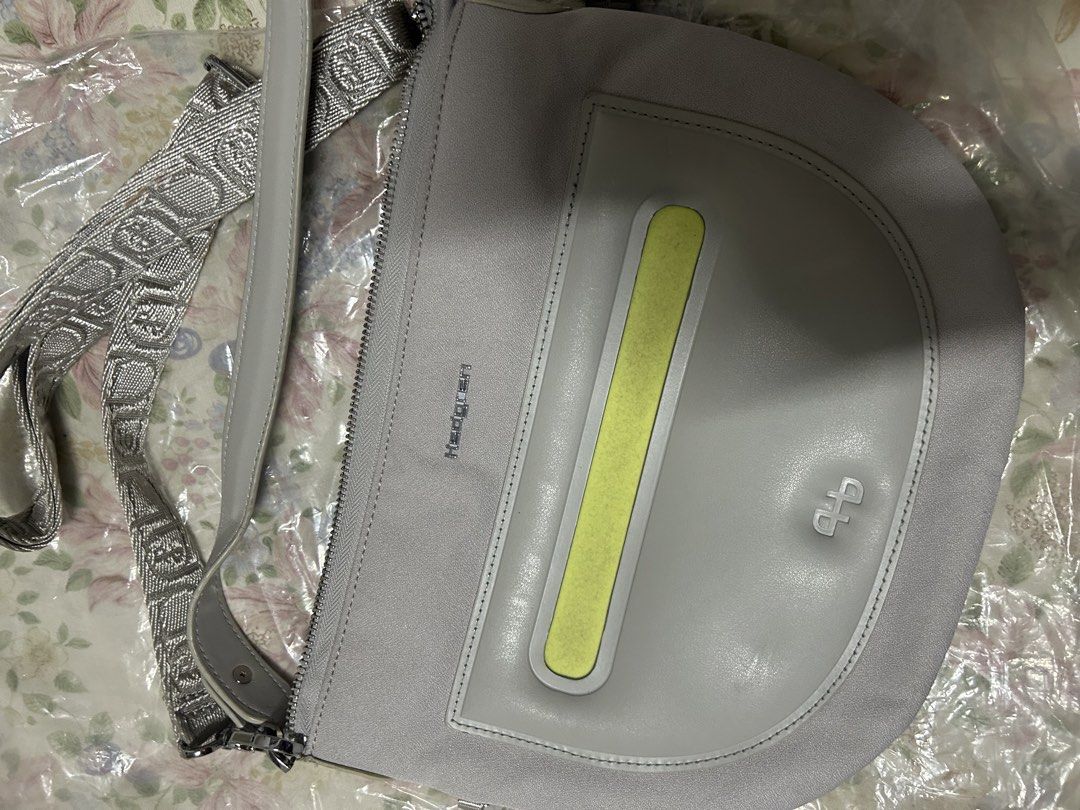 Hedgren Grey Crossbody Bag with Silver Strap (Category: Cross-body Bags) located in Bacoor. Submitted by iamgraxa (Listing ID 1460023053, Image 1). Description: - Grey Hedgren crossbody bag - Unique silver strap with repeating pattern - Front pocket with yellow accent - Zipper closure - Clean and modern design.