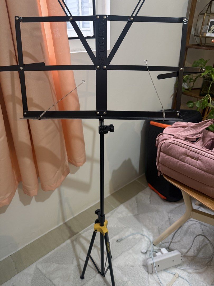 Hercules Music Stand (Category: Music Accessories) located in Manila. Submitted by blanknwhite (Listing ID 1459947342, Image 2). Description: - Black foldable music stand - Sturdy tripod base with yellow accents - Adjustable height for comfortable use - Easy to set up and pack away - Ideal for musicians, practice, or performance.