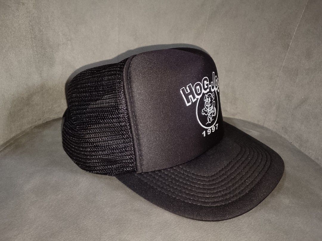 Vintage Hog Jog 1997 Trucker Hat (Category: Caps & Hats) located in Binangonan. Submitted by yuristalin888 (Listing ID 1459914694, Image 3). Description: This vintage black trucker hat features a structured front panel screen-printed with a white "HOG-JOG" graphic, a running cartoon animal mascot inside a circle, and the year "1997" below. It is styled with a slight curved brim and breathable mesh back panels..