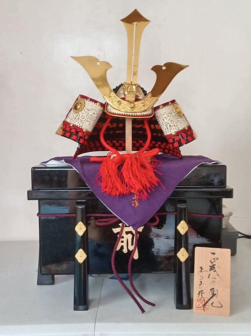Japanese Samurai Helmet Display for Boys' Day (Category: Vintage Collectibles) located in Davao. Submitted by mizzycat62 (Listing ID 1459968368, Image 1). Description: - Traditional Japanese samurai helmet display - Black lacquered base with gold accents - Red and gold helmet with intricate detailing and red tassels - Includes a wooden plaque with Japanese calligraphy - Beautiful decorative piece, ideal for Children's Day (Tango no Sekku).