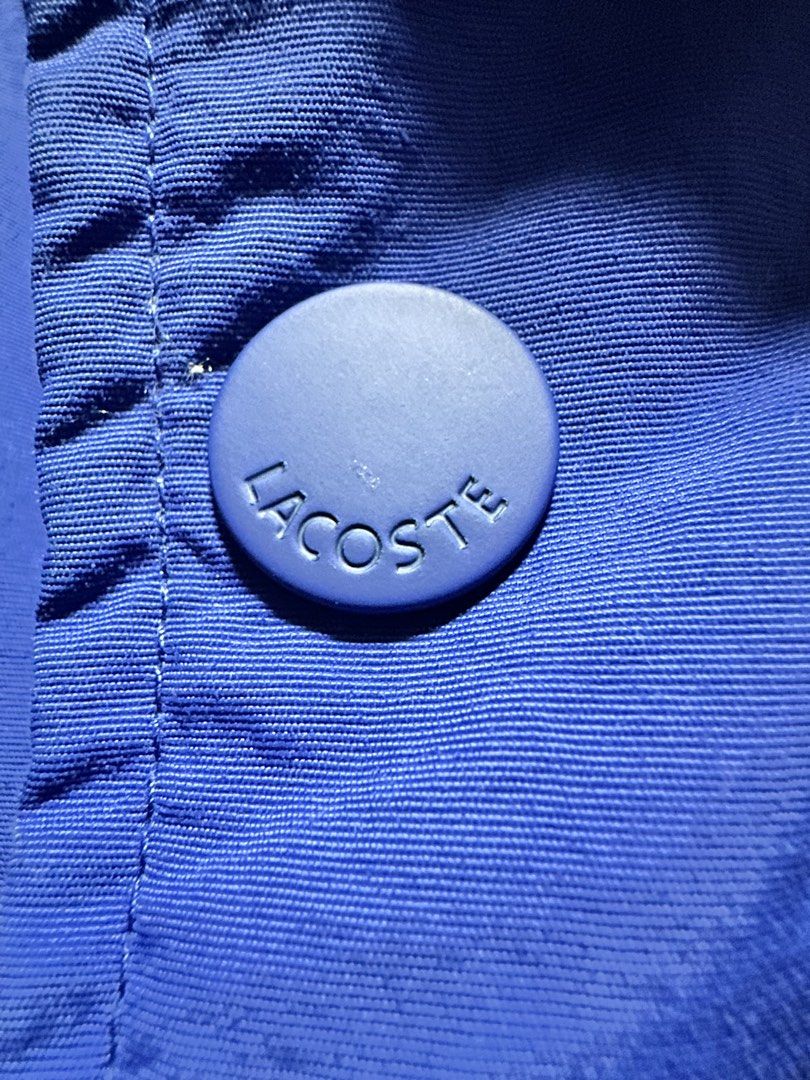 Lacoste Blue Puffer Jacket with Logo (Category: Coats, Jackets and Outerwear) located in Cavite. Submitted by yong_mountaineering (Listing ID 1460043819, Image 3). Description: - Blue puffer jacket from Lacoste - Signature crocodile logo patch on chest - Logo embossed on front buttons - Made in China - Polyester body and hood lining - Polyamide sleeve lining - Acrylic ribbing.