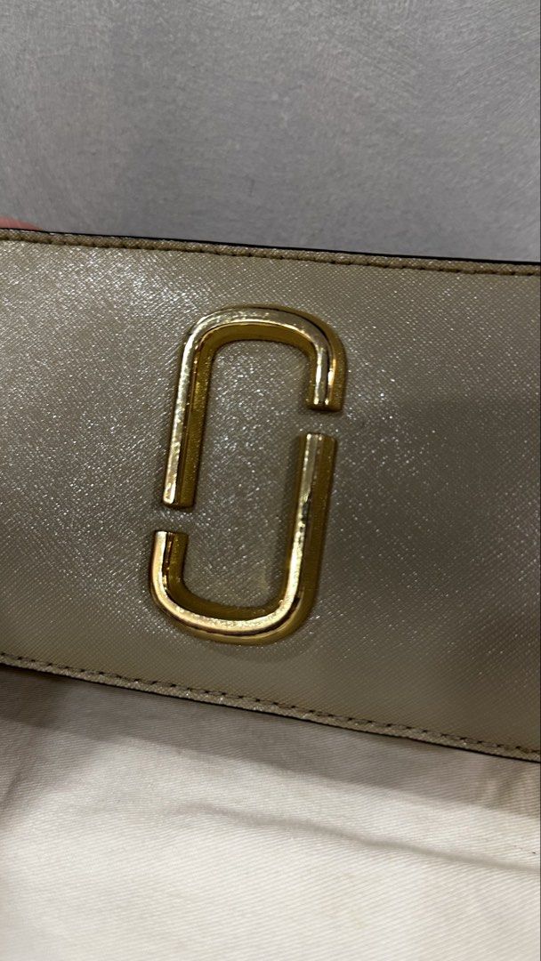 Marc Jacobs Snapshot Camera Bag with Strap (Category: Luxury Bags & Wallets) located in Rizal. Submitted by dumbchowdy (Listing ID 1460037394, Image 2). Description: - Authentic Marc Jacobs Camera Bag - Color: Neutral Beige - Iconic Gold Double J Logo on Front - Comes with Black and Yellow Striped Strap - Includes Original Dust Bag - Ideal for Everyday Use.