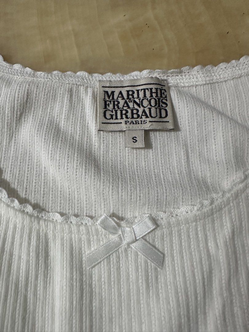 Marithe Francois Girbaud White Ribbed Tank Top Size S (Category: Sleeveless) located in Manila. Submitted by jessj30 (Listing ID 1460002276, Image 1). Description: - White ribbed tank top by Marithe Francois Girbaud - Features a small bow detail at the neckline - Subtle logo emblem on the front - Sleeveless design - Scalloped hem - Made from a comfortable cotton blend - Ideal basic piece for everyday outfits.